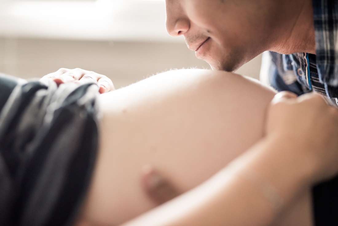 détail des lèvre d'un homme sur le ventre d'une femme enceinte